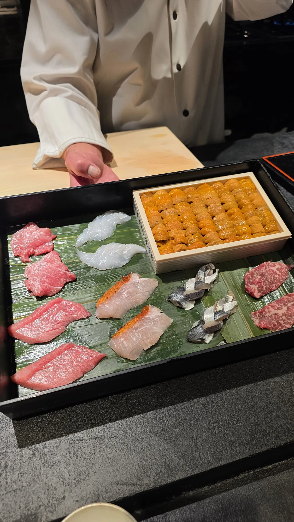 Chef showing the night's produce: tuna, hata, straw-smoked kinmedai, cured kohada, wagyu, Hokkaidō uni